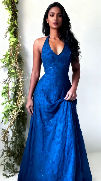 Woman wearing a blue evening gown against a white background with greenery.